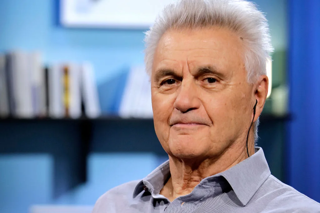 A portrait of author John Irving against a blue background