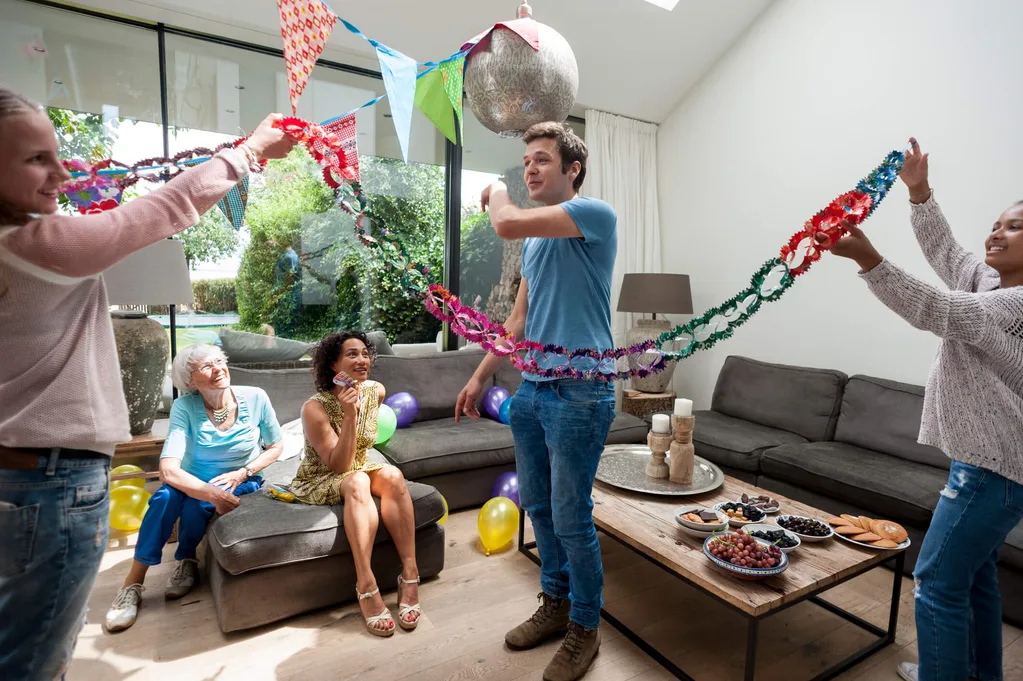 Guy in middle of room helping setup birthday streamers