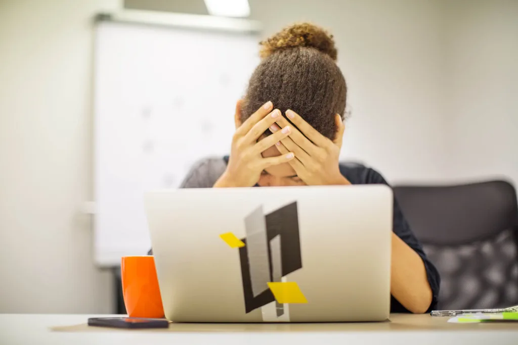 Girl holding her head in her hands in front of laptop