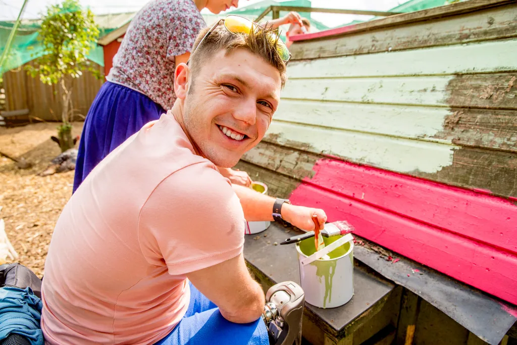 Man painting a wooden wall on a volunteerism trip