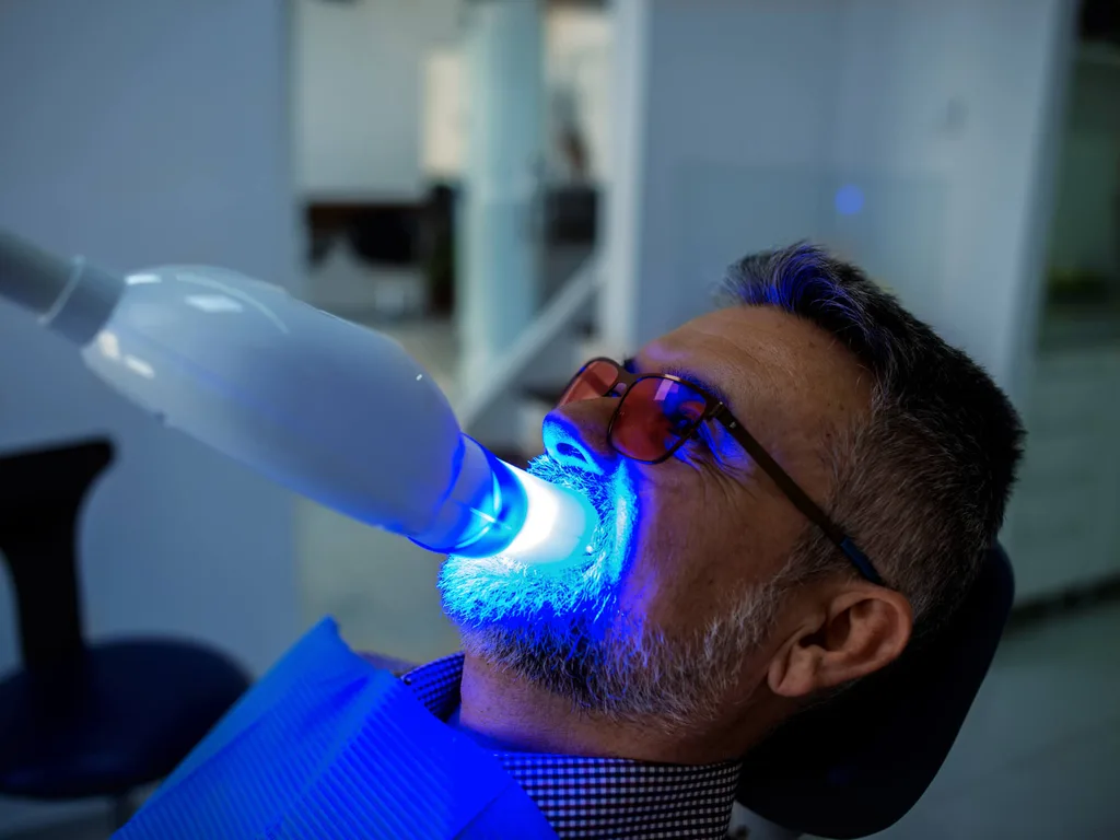 Man in dentist chair getting his teeth whitened with a laser