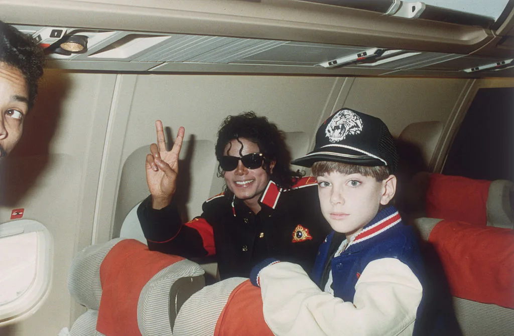 Michael Jackson sitting with 10 year old Jimmy Safechuck on his tour plane