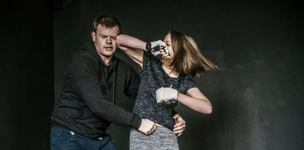 A woman hitting a man using martial arts