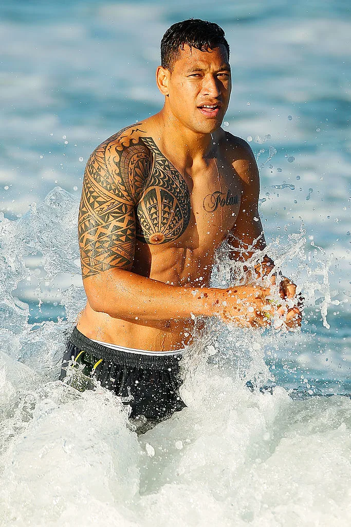 Israel Folau in the ocean showing off his arm tattoos