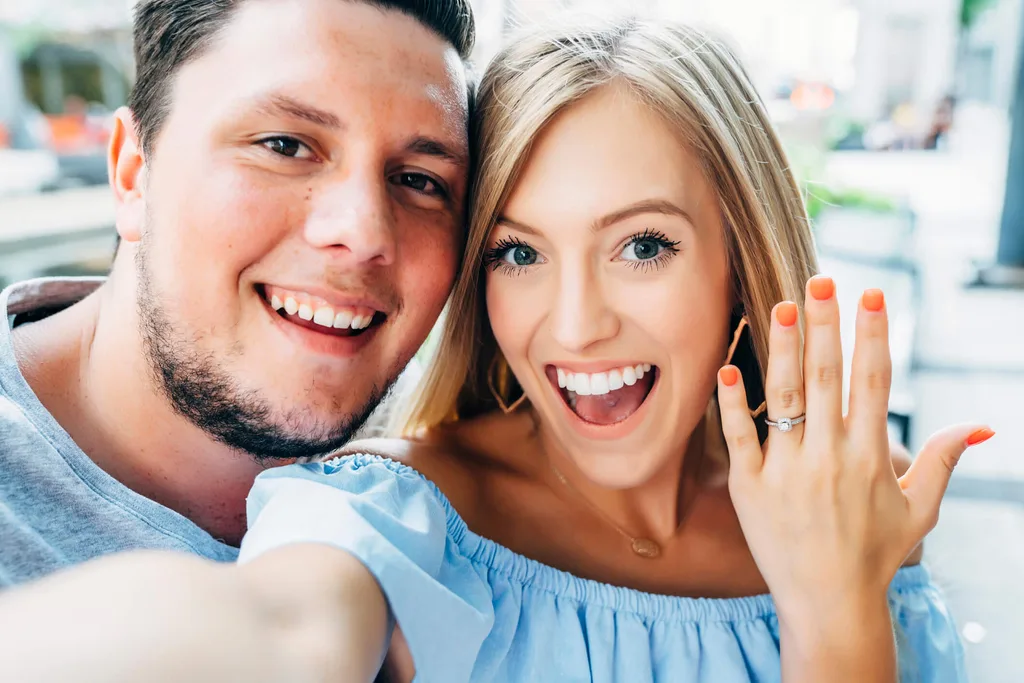 A woman showing off her engagement ring next to her fiance