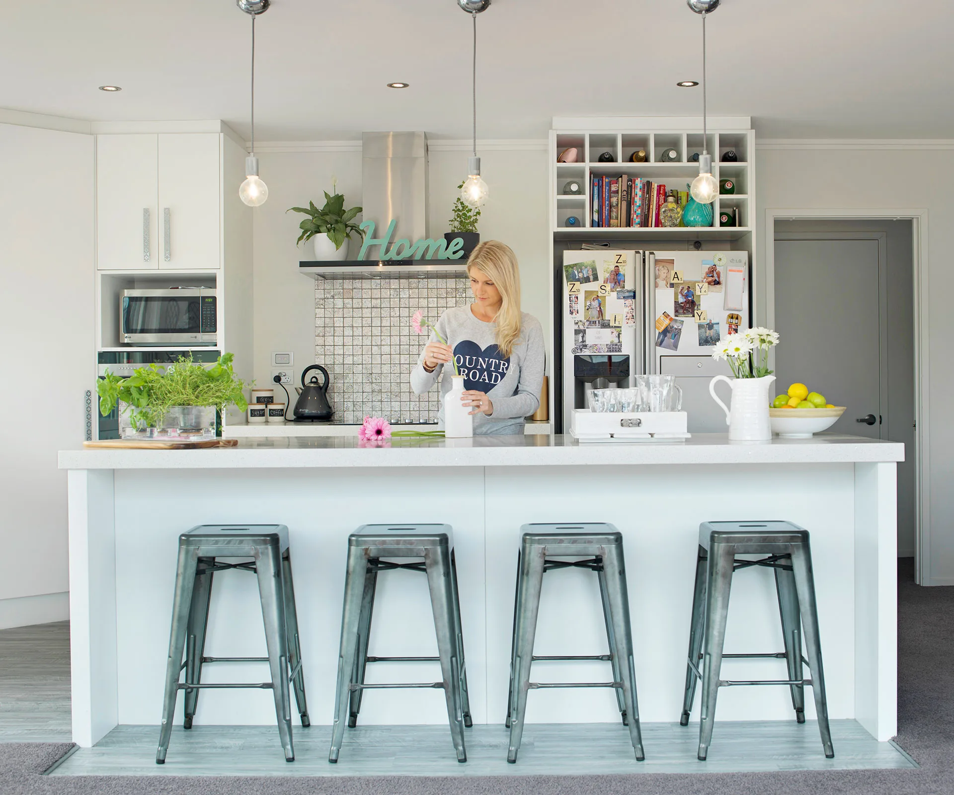 Metallic stools, the ‘tinfoil’ tiled splashback and naked bulb lighting installations complement the brushed aluminium appliances. 