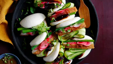 Six pork belly bao buns with cucumber and pickles ready to be eaten