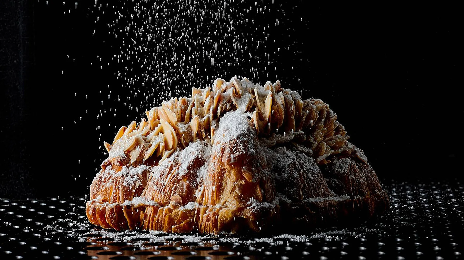 Lune Croissanterie almond croissant with icing sugar showering down onto it