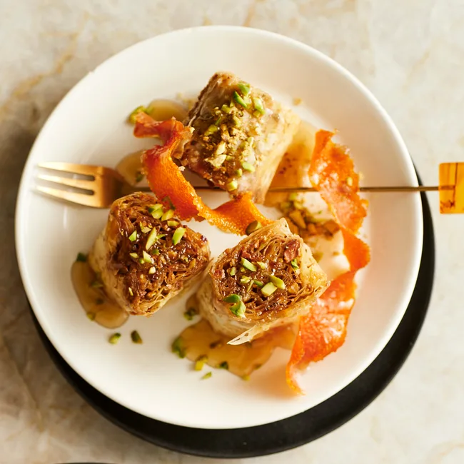 Baklava rolls with pistachio on a white plate