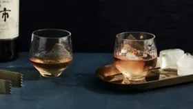 Whisky bottle and two whisky glasses with ice and tongs