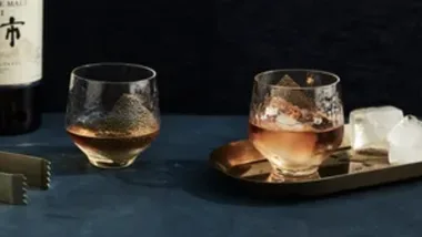 Whisky bottle and two whisky glasses with ice and tongs