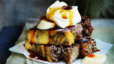 A close-up photograph of toasted banana bread with ice-cream and butterscotch sauce
