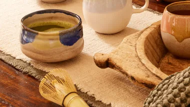 cups of matcha and whisk on a table