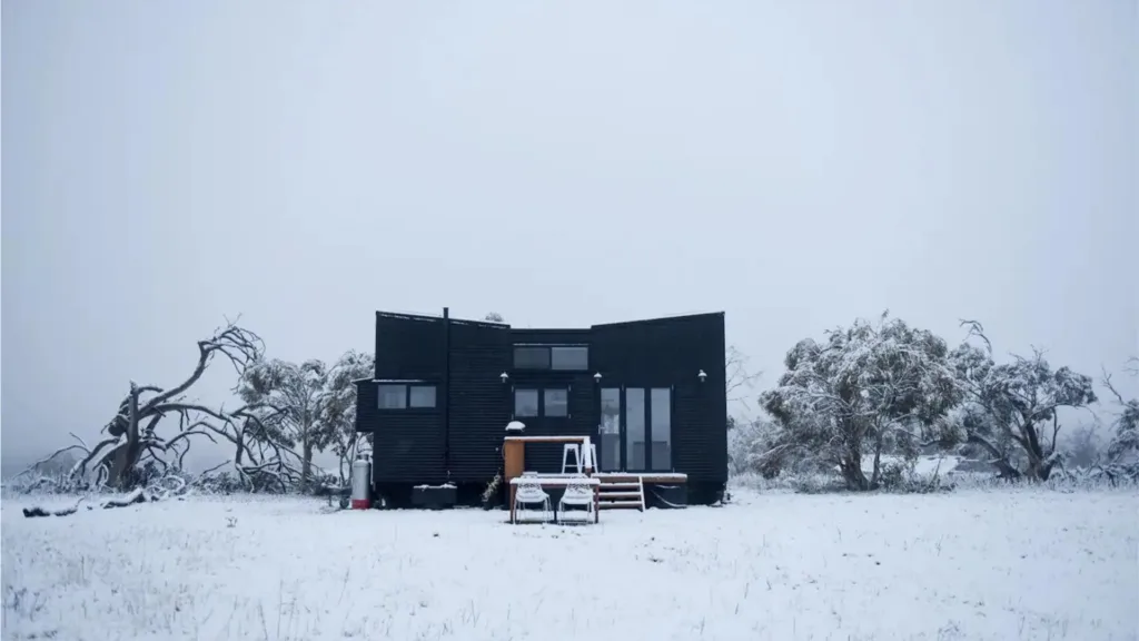 Wintry photo of black exterior Jindabyne Airbnb in snow