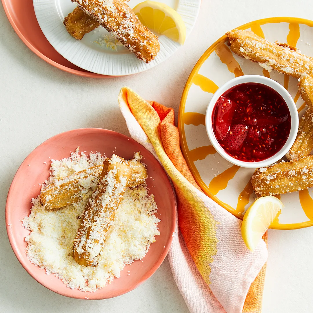 Lemon sugar churros with mixed berry compote on terracotta bowls.