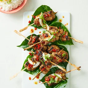 Lemongrass and palm sugar lamb skewers served on a betel leaf.