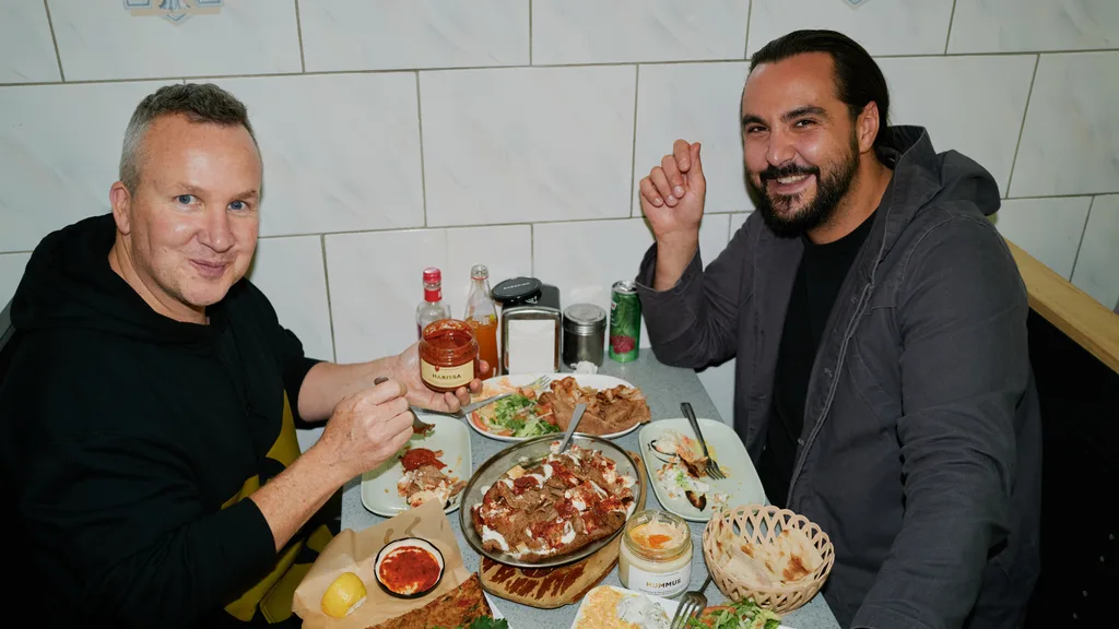 Tom Sarafian and Nathan Toleman sit with a Levantine spread of food. 