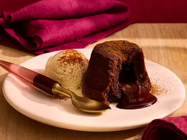 Chilli and chocolate lava cake on plate with spoon and red napkins.