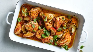 Cider-braised chicken with Brussels sprout and apple salad in white dish.