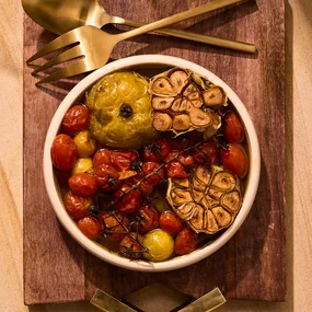 Confit garlic and heirloom tomatoes on wooden board.