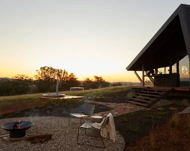 NSW tiny home stay Gilay Estate at sunset with lit outdoor fire pit, landscaped garden and hot tub