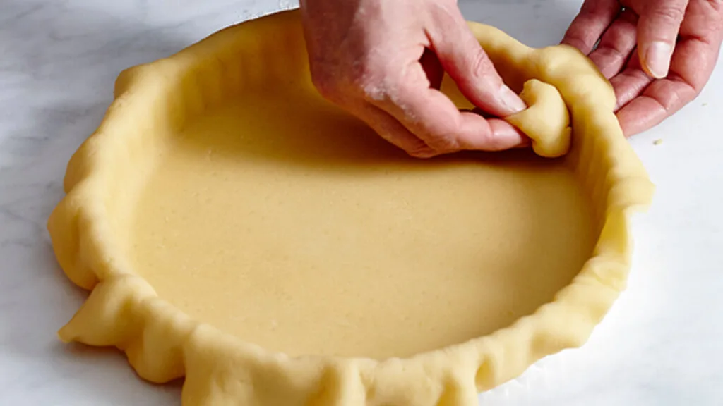 Pushing the pastry to the edges of the tin is easier when you use a bit of leftover pastry rather than your fingers.