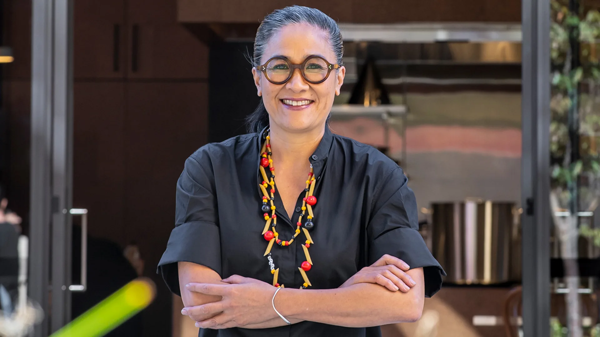 Chef Kylie Kwong outside Lucky Kwong. Kwong is smiling, wearing round glasses and has her arms crossed