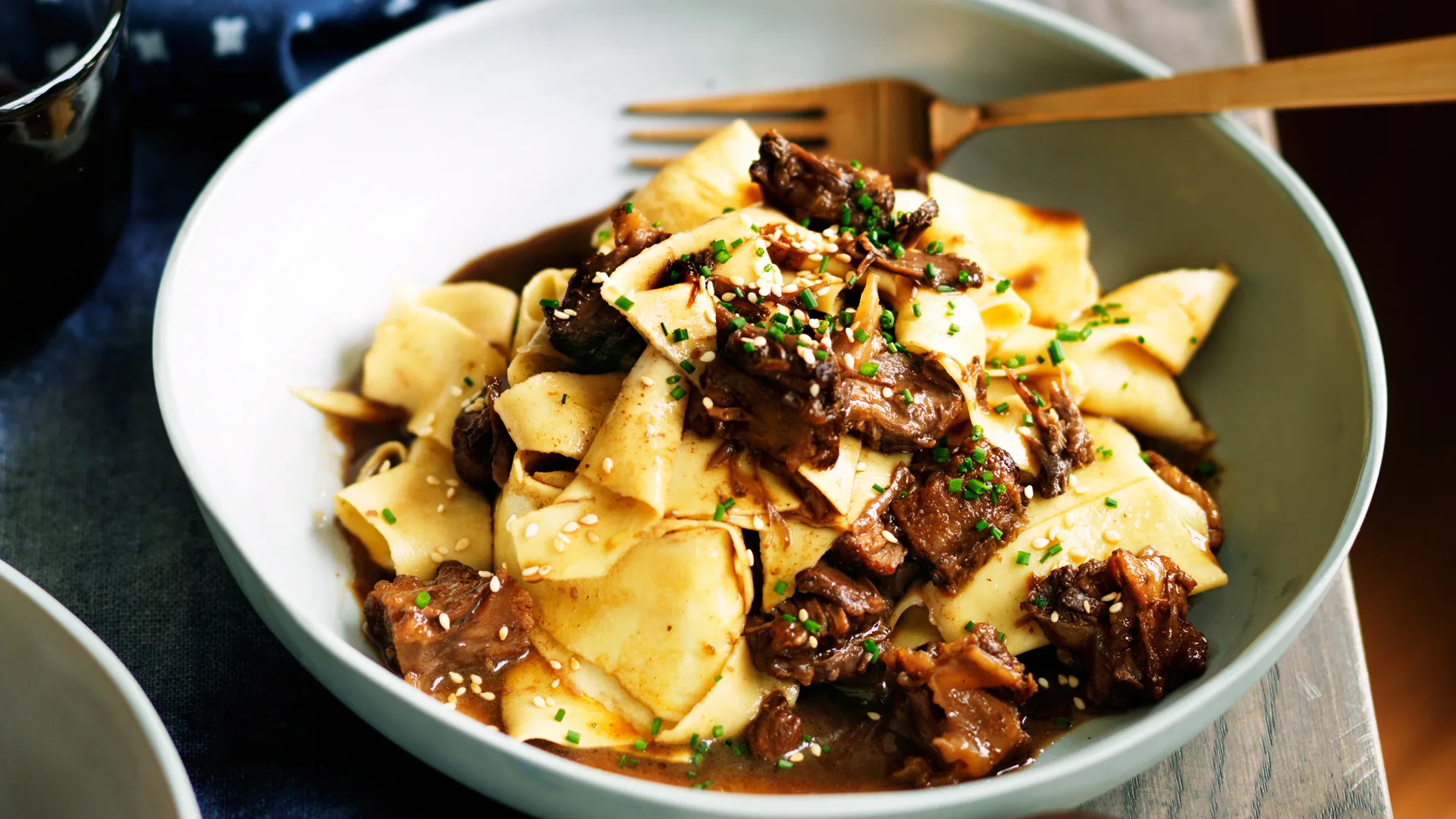 Types of pasta: Maltagliati pasta with braised oxtail and black vinegar in white bowl with gold fork