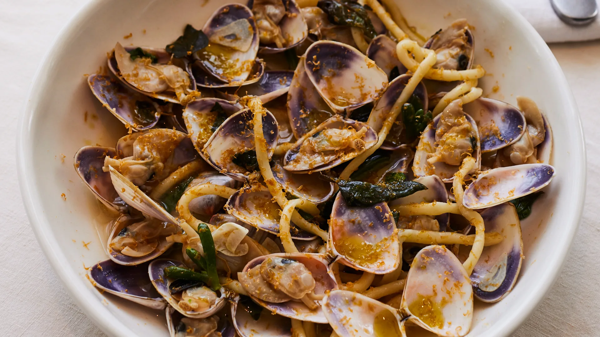 Pici pasta with opened cooked pipis in whote bowl