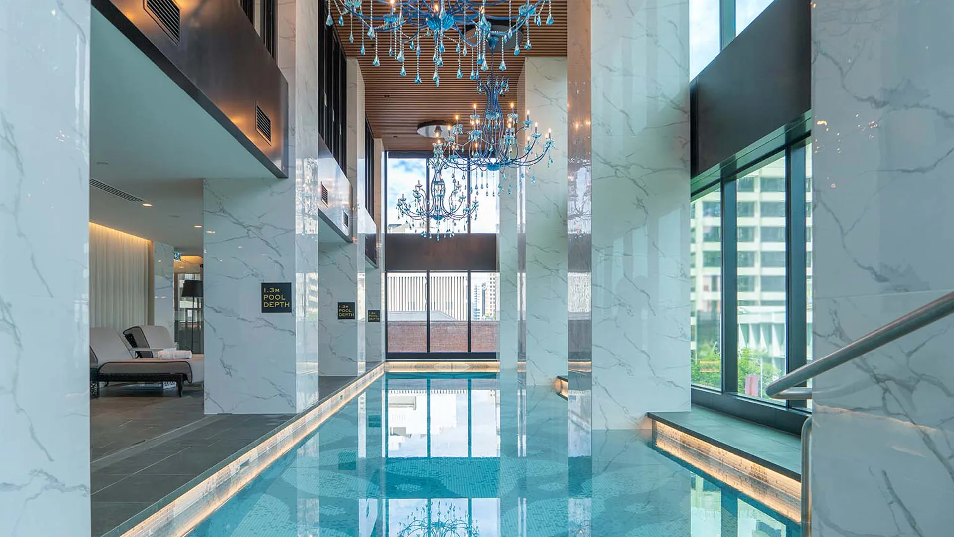 Indoor pool with marble columns and overhanging blue chandeliers at luxury Adelaide hotel, Sofitel Adelaide
