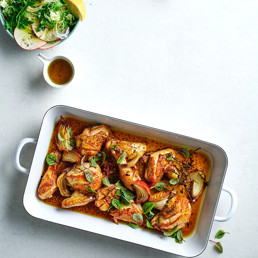 Cider-braised chicken recipe with Brussels sprout and apple salad in white dish.