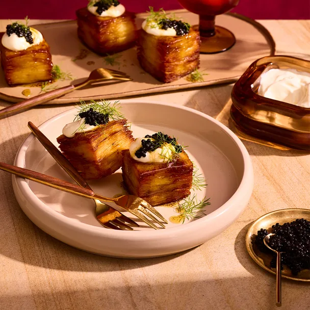 Salt and vinegar 15-hour potatoes with creme fraiche and caviar in pink bowl.