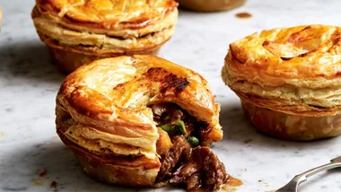 Beef rendang mini meat pie with flaky folden pastry and filling spilling out of biten pastry