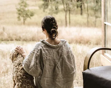 woman and a dog sit in a tiny cabin looking out to a field