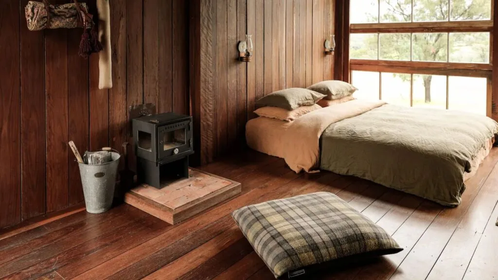 a timber cabin with small fireplace and queen bed