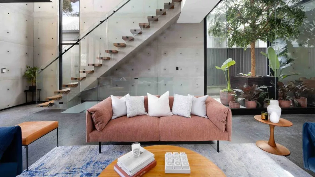 An industrial contemporary style living room with a colourful couch and staircase behind