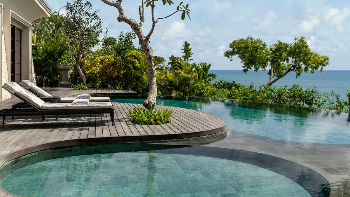 Circular swimming pools and sundeck overlooking ocean at one of the best Bali resorts for families, Four Seasons at Jimbaran Bay