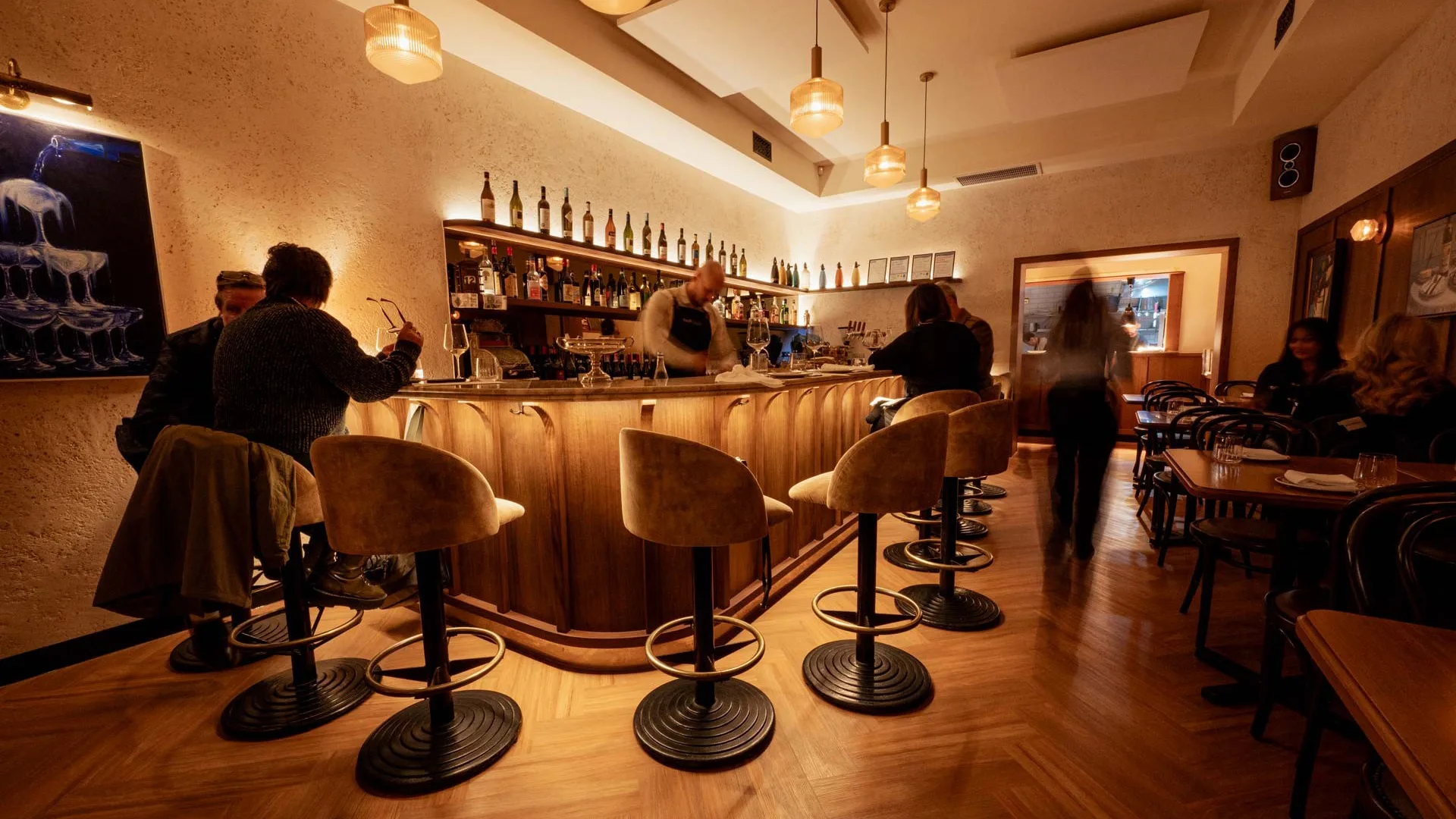 People sitting at the counter with warm lighting at Melbourne wine bar Bar Olo