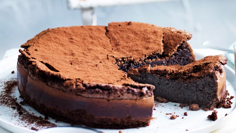 Photo of a fudgy, chocolate cake with one slice out