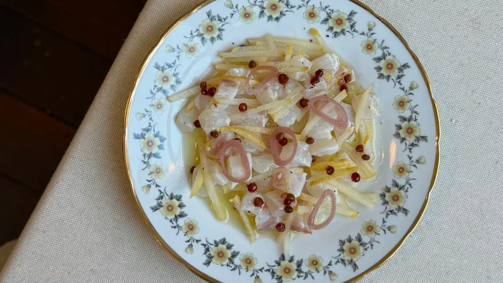 Cubes of raw fish sprinkled with slicked pickled pear and onions served on a retro-style plate at Staguni.