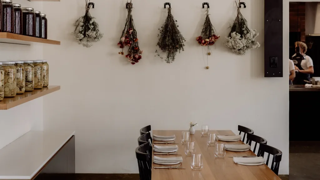 A photo of the interiors of The Agrarian Kitchen Restaurant, with dried flowers hanging from the walls and jars of pickled vegetables on shelves.