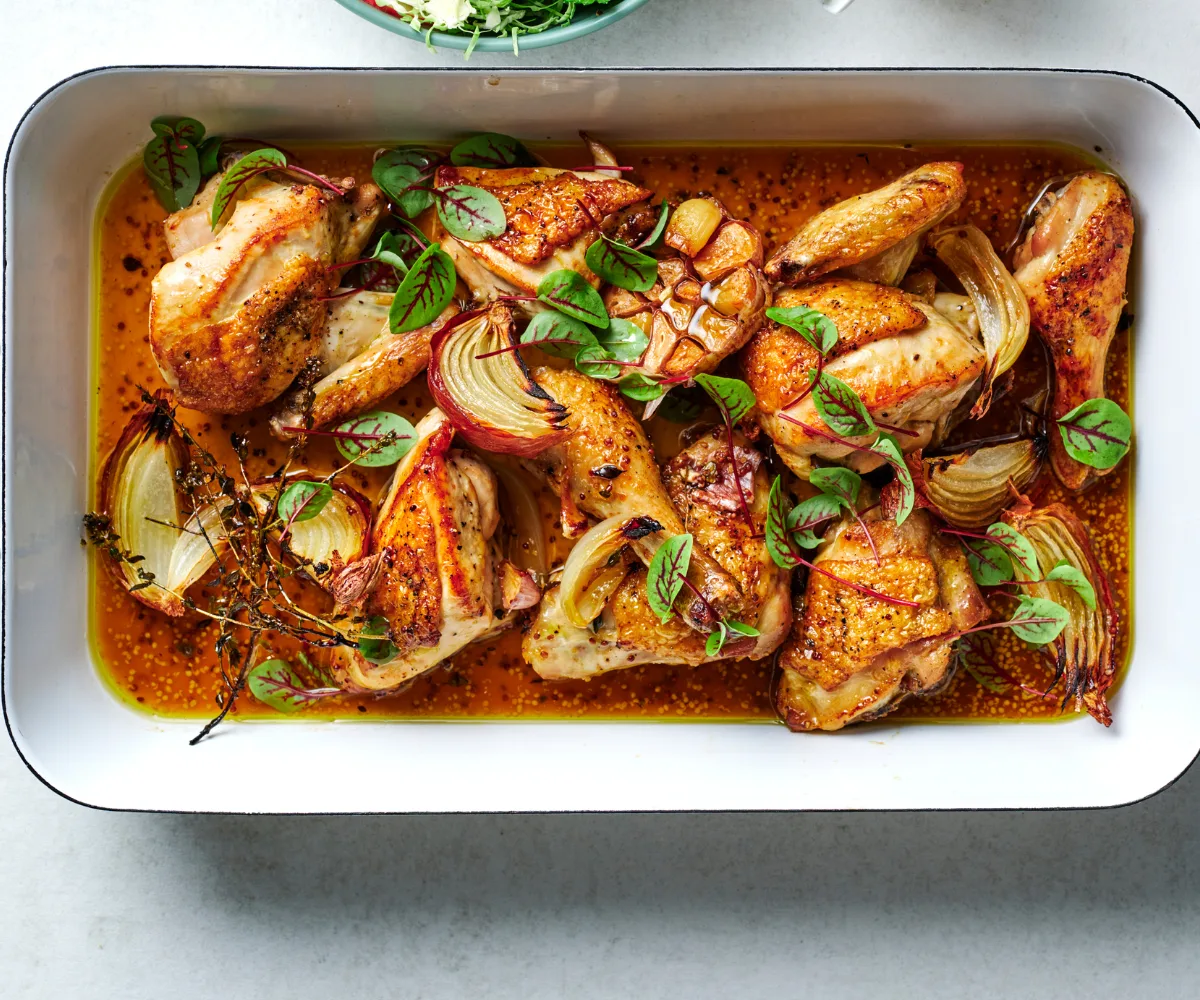 Cider-braised chicken recipe with Brussels sprout and apple salad in white dish.