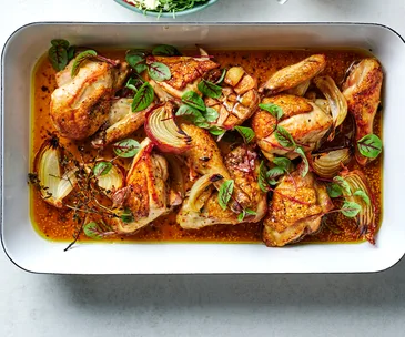 Cider-braised chicken recipe with Brussels sprout and apple salad in white dish.