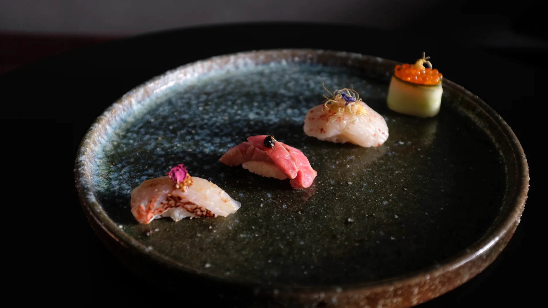 A ceramic plate with four nigiri sushi dishes as part of the omakase