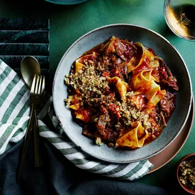 Calabrian chilli and lamb stracci pasta with striped napkin and cutlery.