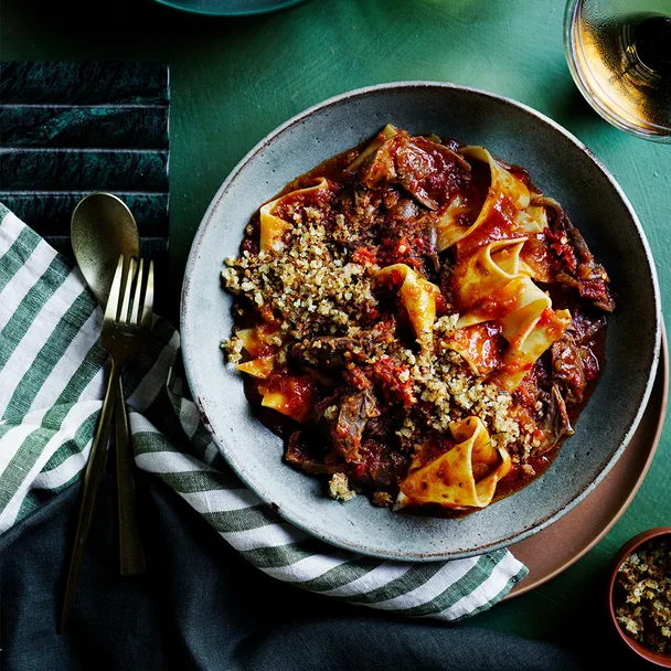 Calabrian chilli and lamb stracci pasta with striped napkin and cutlery.