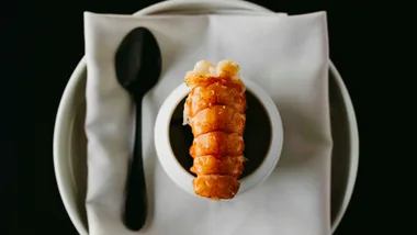 A close-up photo of a plate with marron and steamed egg custard. A black spoon is next to it.