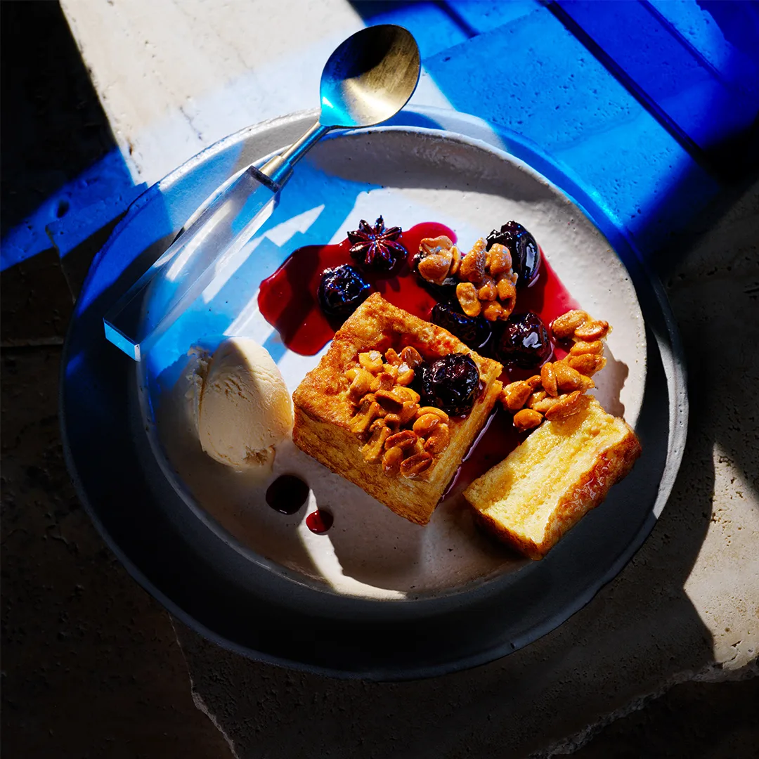 Hong Kong French toast with smoked cinnamon ice-cream and cherry with spoon on blue background.