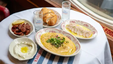 Five plates of food on a round table at Kafeneion.