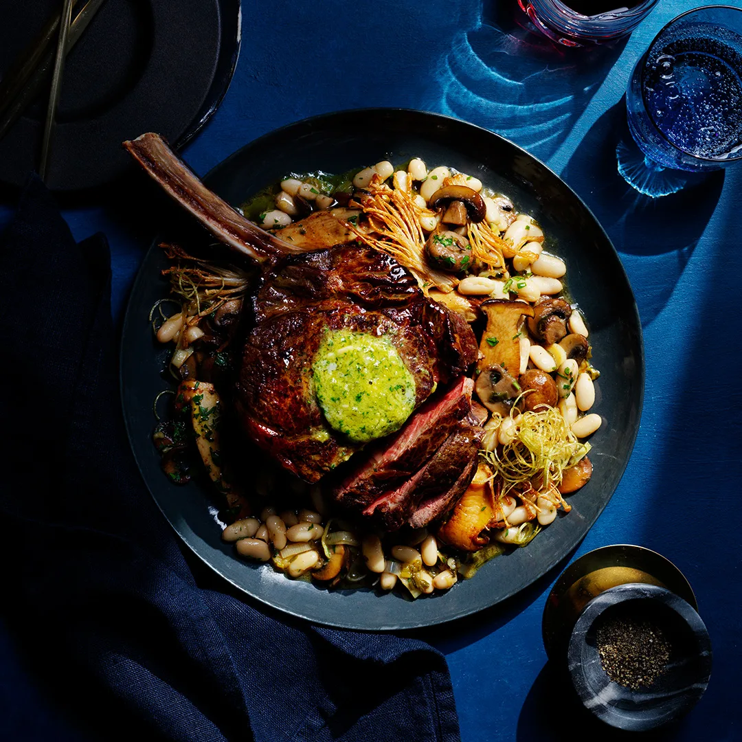 Koji rubbed steaks with whisky and miso butter on blue background.